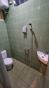 a bathroom with a shower and a toilet and a sink at Sukun Hotel Cilacap in Cilacap +3 photos