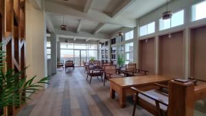a dining room with tables and chairs and windows at Sukun Hotel Cilacap in Cilacap