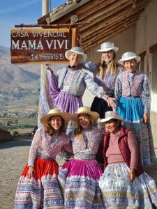 Un groupe de femmes en robes posant une photo dans l'établissement Casa vivencial Mamá Vivi, à Coporaque