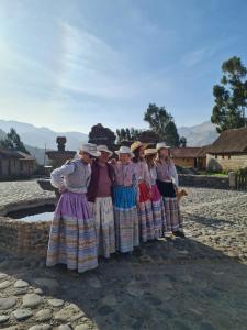 un grupo de mujeres vestidas tradicionales posando para una foto en Casa vivencial Mamá Vivi, en Coporaque