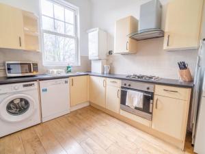 eine Küche mit weißen Schränken, einer Waschmaschine und einem Trockner in der Unterkunft Pass the Keys Cosy 2 Bedroom Apartment near city centre in Nottingham