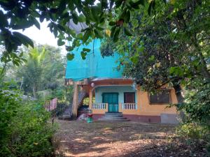 a house with a blue roof in a forest at Terrace House Goa in Arambol