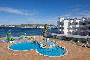 un complejo con piscina junto al océano en Playa Bella Apartments, en Bahía de San Antonio