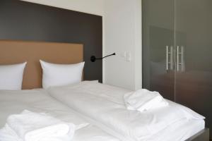 uma cama com lençóis brancos e um candeeiro em Resort Deichgraf Resort Deichgraf 31-03 em Wremen