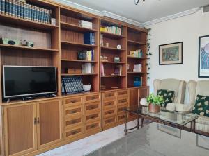 una sala de estar con un gran centro de entretenimiento de madera con TV en Bonito ático en la judería de Córdoba, en Córdoba