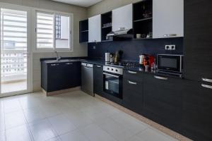 a kitchen with black cabinets and a white tile floor at Beautifully Designed 3BR Apartment+ Panoramic View in Rabat