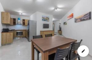 a kitchen with a wooden table and chairs in a room at Marsaxlokk Two Bedroom Apartment 1 minute away from the seafront in Marsaxlokk