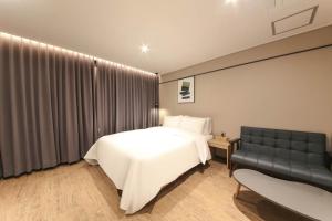 a bedroom with a white bed and a couch at HOUND HOTEL sasang branch in Busan