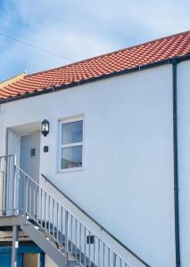 a white house with a staircase and a window at The Butcher's Flat Seahouses in Seahouses