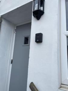 una luz negra en una pared blanca al lado de un edificio en The Butcher's Flat Seahouses, en Seahouses