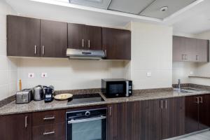 a kitchen with wooden cabinets and a counter top at Maison Privee - Modern Urban Retreat in the Heart of Dubai Marina in Dubai