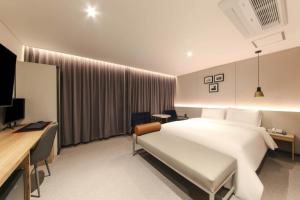 a bedroom with a large white bed and a desk at HOUND HOTEL sasang branch in Busan