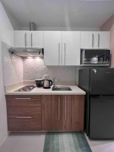 a kitchen with white cabinets and a black refrigerator at Studio unit in Prime Location in Davao City