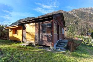 a small house in a field with mountains in the background at Le Petite Chalet Tourmente in Chamonix-Mont-Blanc