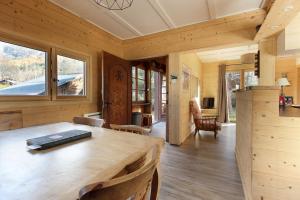 a dining room with a large wooden table and windows at Le Petite Chalet Tourmente in Chamonix-Mont-Blanc