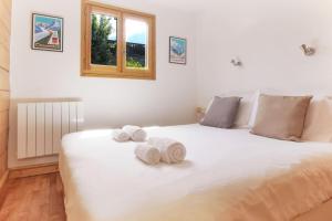a bedroom with a large white bed with towels on it at Chalet Kandahar - Piscine intérieure - Parc & Lac des Chavants - Escalade - Sentiers de Randonnée in Les Houches