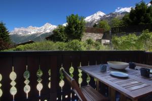 a wooden table on a balcony with mountains in the background at Chalet Kandahar - Piscine intérieure - Parc & Lac des Chavants - Escalade - Sentiers de Randonnée in Les Houches