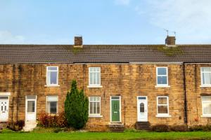 a brick house with a green door and a tree at River-Twine in Croxdale