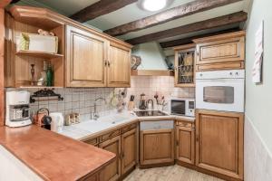 una cocina con armarios de madera y electrodomésticos blancos en Clos de l'Ours - 2 chambres - Jardin privé, en Chamonix-Mont-Blanc