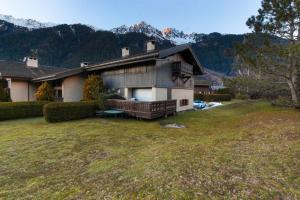 una casa con un gran patio con montañas al fondo en Chalet Ancelles - Les Praz - Golf - Vue Mont-Blanc - Randonnées, en Chamonix-Mont-Blanc