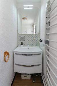 La salle de bains blanche est pourvue d'un lavabo et d'un miroir. dans l'établissement Le Petit Cocon, aux Houches