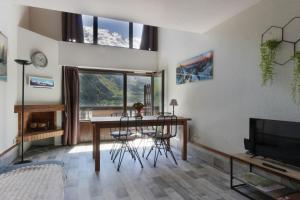 uma sala de estar com uma mesa e cadeiras e uma televisão em Le Crêtet Mont-Blanc em Chamonix-Mont-Blanc