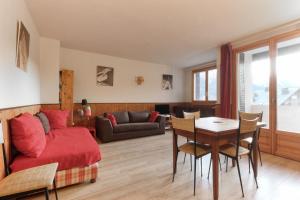 ein Wohnzimmer mit einem roten Bett und einem Tisch in der Unterkunft Les Pècles Mt Blanc - Chamonix Center in Chamonix-Mont-Blanc
