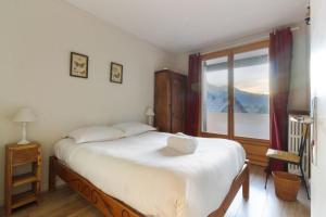 ein Schlafzimmer mit einem großen Bett und einem Fenster in der Unterkunft Les Pècles Mt Blanc - Chamonix Center in Chamonix-Mont-Blanc