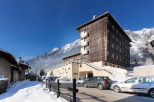 un bâtiment avec des voitures garées dans un parking avec des montagnes dans l'établissement Les Pècles Mt Blanc - Chamonix Center, à Chamonix-Mont-Blanc