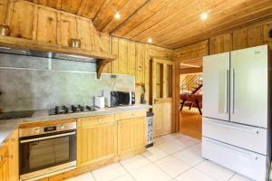 eine Küche mit Holzschränken und einem weißen Kühlschrank in der Unterkunft Le Chalet des Chavants - 8ch - 300m2- Grand Jardin - Vues du Mont-Blanc in Les Houches