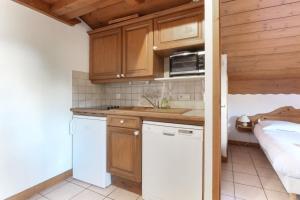 a kitchen with wooden cabinets and a white refrigerator at Le Goûter - Ski-in ski-out - Indoor Pool in Les Houches +6 photos