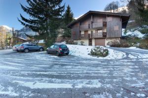 two cars parked in a parking lot in front of a building at Le Goûter - Ski-in ski-out - Indoor Pool in Les Houches