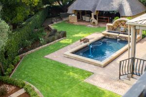 a backyard with a swimming pool in the grass at The Wild Olive Guesthouse in Centurion