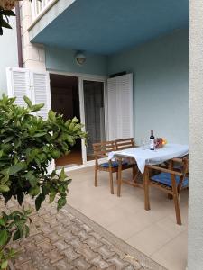 einen Tisch und Stühle auf einer Terrasse mit einer Flasche Wein in der Unterkunft Apartments Blue House in Korčula
