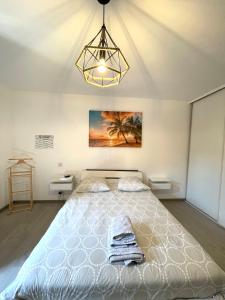 - une chambre avec un grand lit blanc et un lustre dans l'établissement Havre de paix Annécien, à Meythet