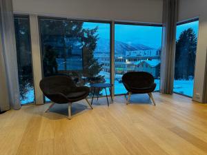 2 sillas y una mesa en una habitación con ventanas grandes en North Apartment City house. en Tromsø