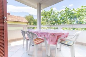 a white table and chairs on a porch with a pink table at Apartments Antica with a balcony in Baška