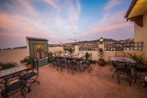 patio ze stołami i krzesłami na balkonie w obiekcie Charming Riad Ouliya in Fs with authentic Moroccan design w Fezie