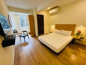 Sanctum Suites Richmond Road Bangalore في بانغالور: غرفة نوم بسرير ومكتب وكرسي