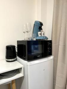 eine Mikrowelle auf einem Schrank mit Weingläsern in der Unterkunft Gamma - studio 2 pers - centre / proche hôpital in Montereau-faut-Yonne