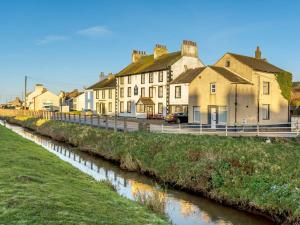 a row of houses next to a river at 1 bed property in Allonby 28790 in Allonby