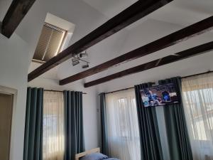 una camera da letto con tende verdi e TV a parete di Camera Junior 5 persoane Paulownia Garden a Cristian