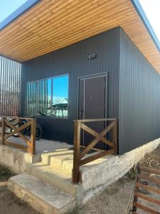 a black building with a wooden door and stairs at Vavilon in Karakol