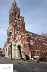 a large brick building with a clock tower at L'évasion du Coquelicot in Albert