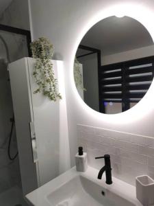 a white bathroom with a sink and a mirror at L'évasion du Coquelicot in Albert