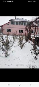 ein rosafarbenes Gebäude mit Schnee davor in der Unterkunft Vila Lumi in Constanţa