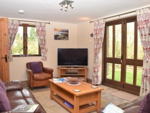 a living room with a tv and a couch and a table at 2 Bed in Widemouth Bay WOOWW in Poundstock
