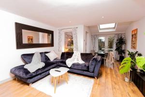 uma sala de estar com um sofá preto e uma mesa em Beautiful West Didsbury 4BR Home em Manchester