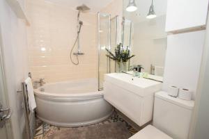 a bathroom with a toilet and a tub and a sink at Beautiful West Didsbury 4BR Home in Manchester