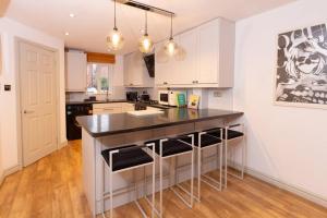una cocina con encimera negra y armarios blancos en Beautiful West Didsbury 4BR Home, en Mánchester
